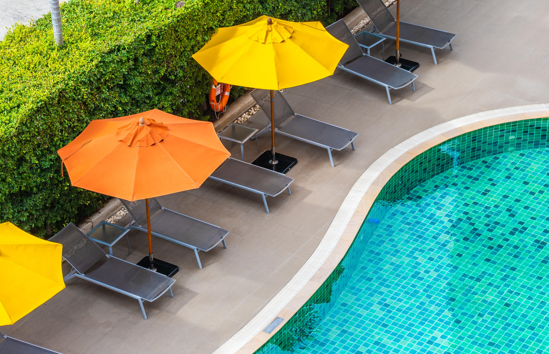 Orange and yellow umbrellas line a hotel pool.