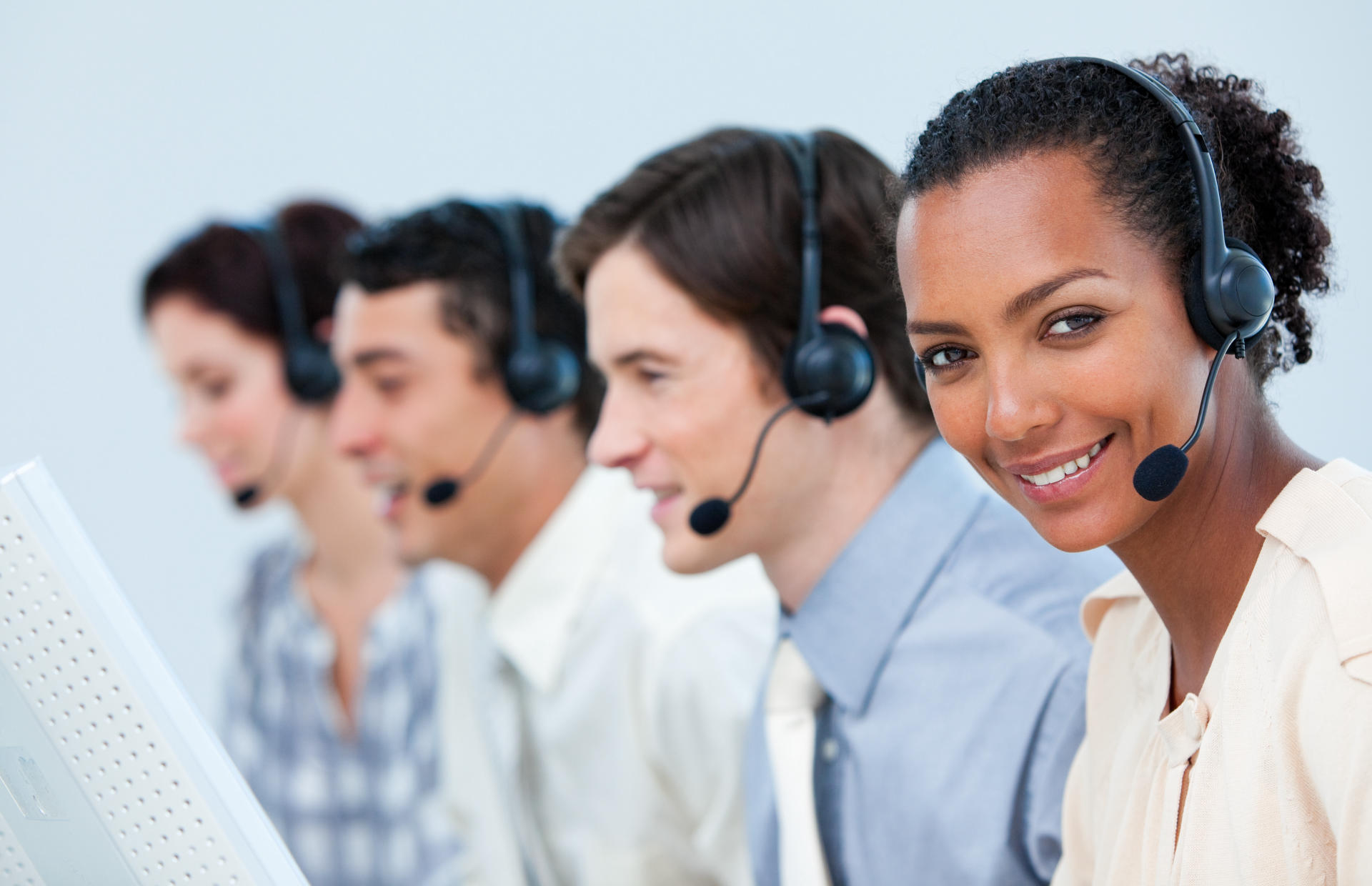 A group of four call center agents are wearing headsets.