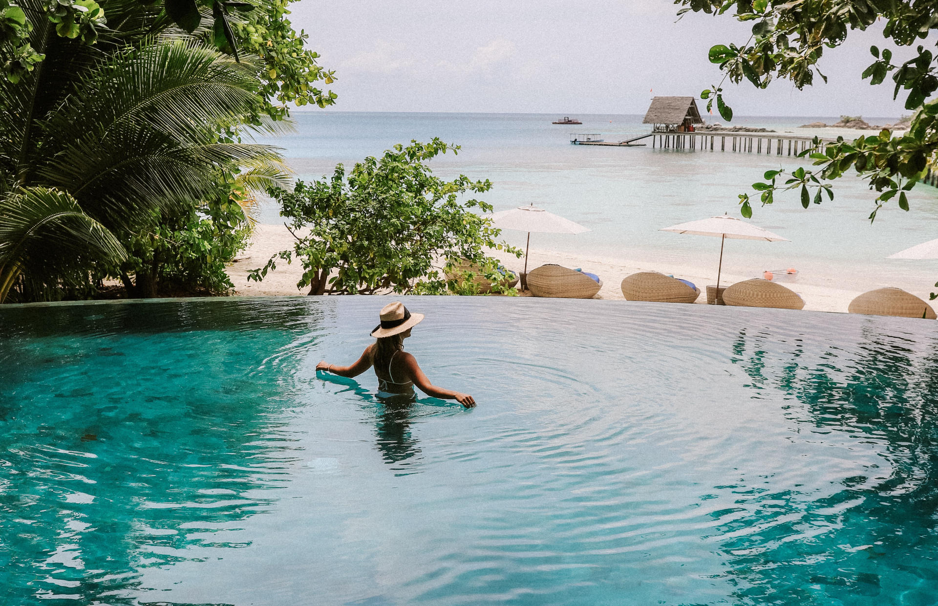 A person wades in the pool that overlooks the ocean.