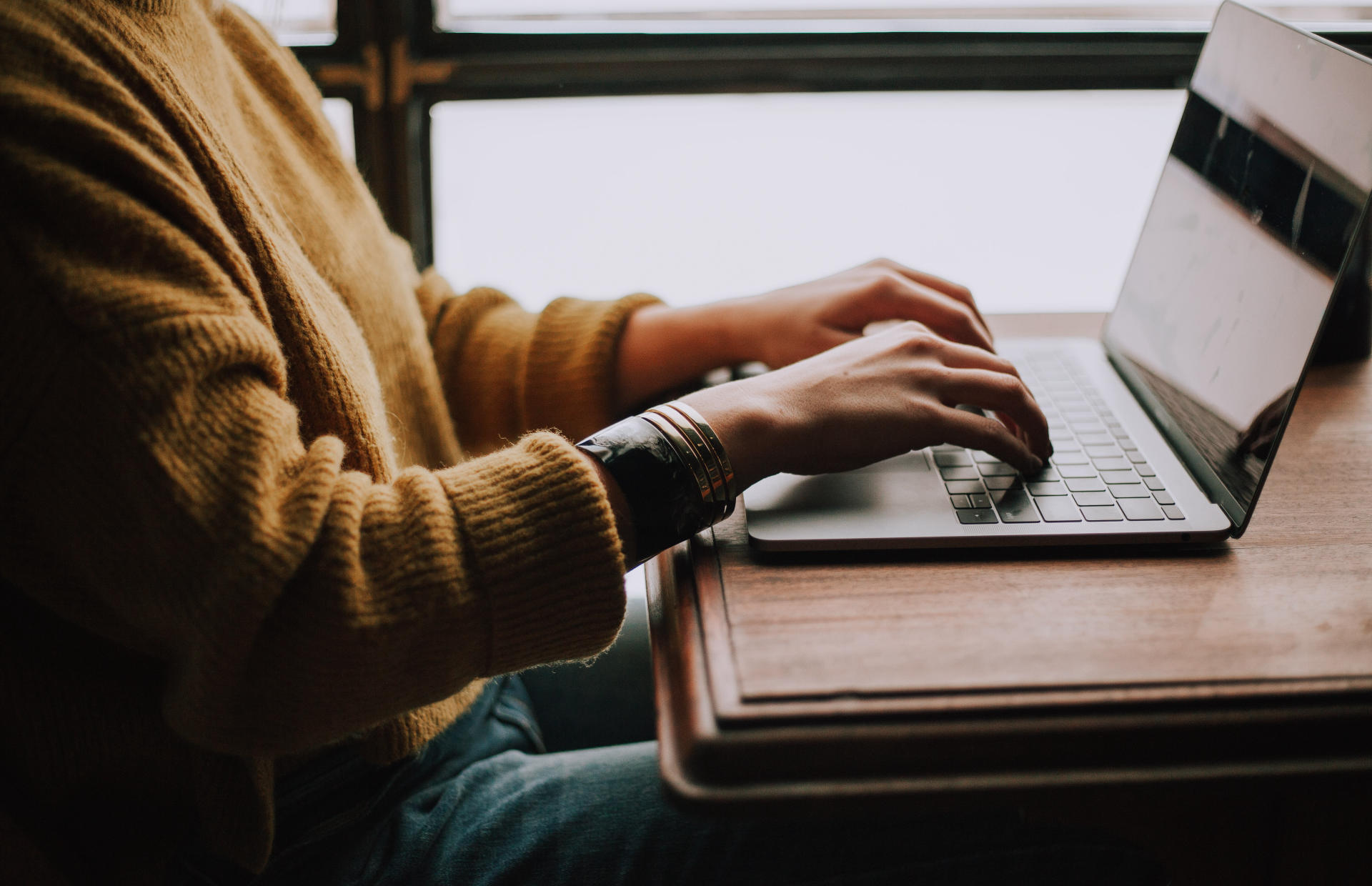 A person sits and types on their computer.