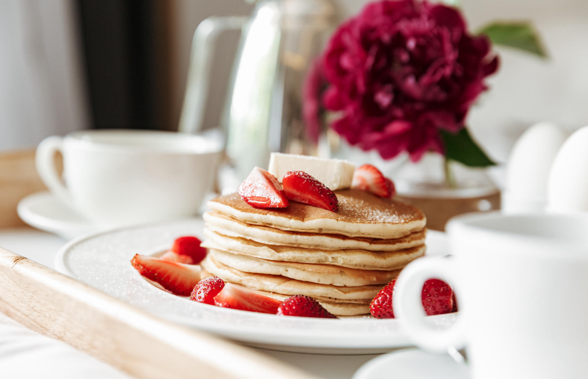 A stack of pancakes has strawberry slices on top.