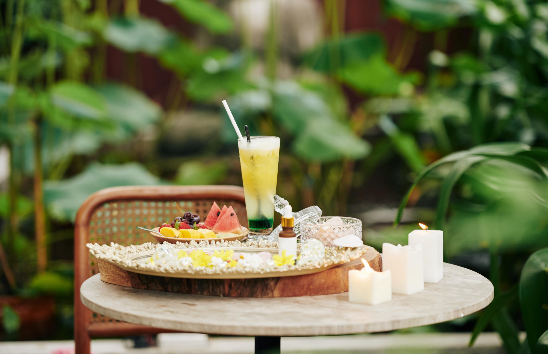 A cocktail sits on a small table with a side of fruit.