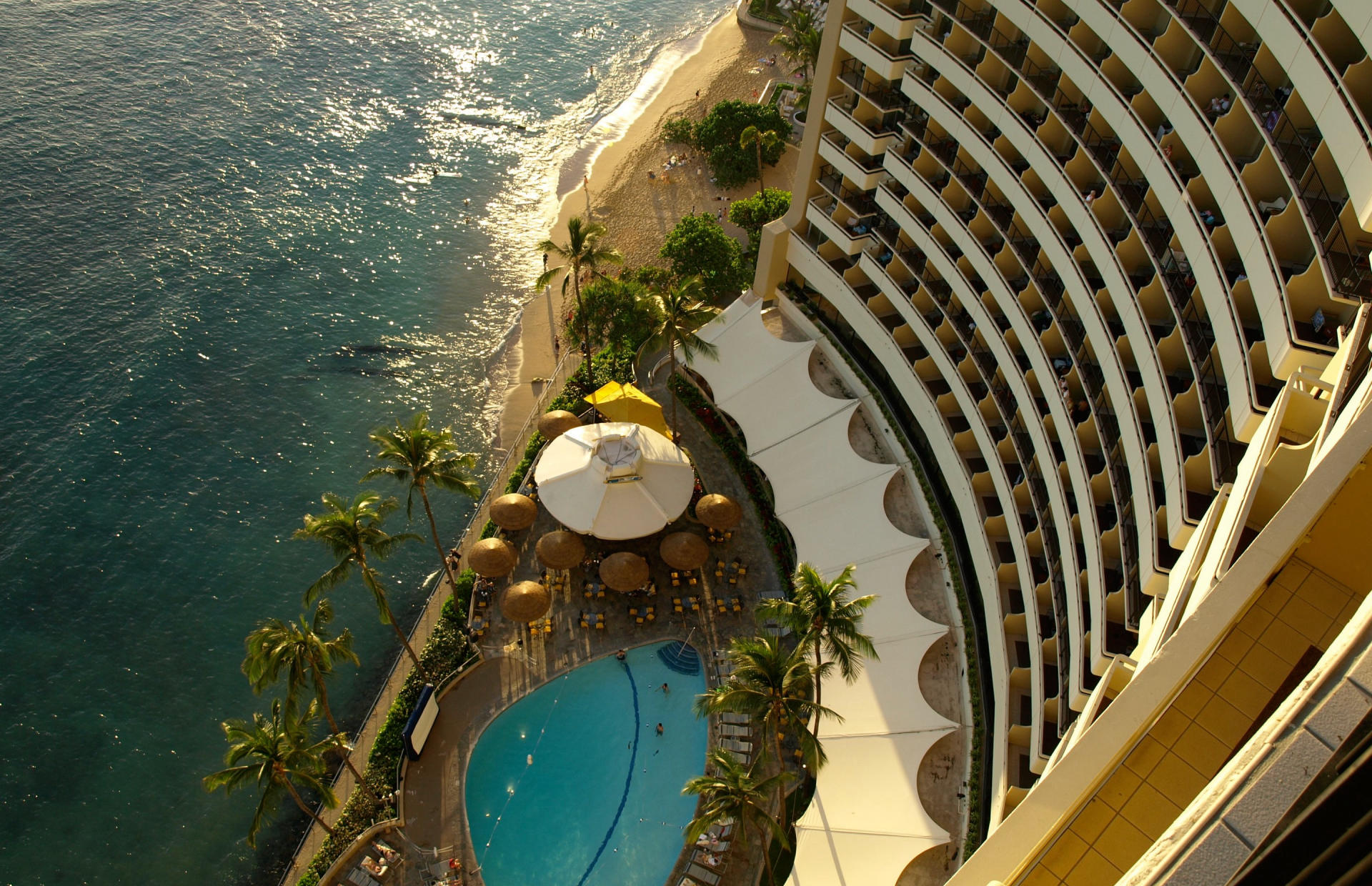 A multi-story hotel building sits by the ocean.