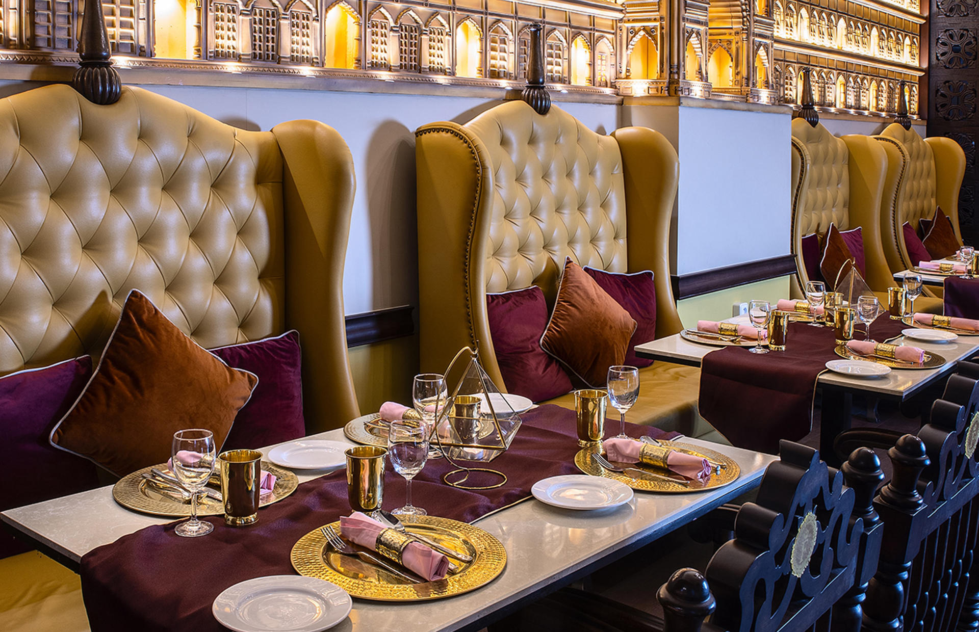 A hotel dining area is decorated wit ornate chairs and place settings.