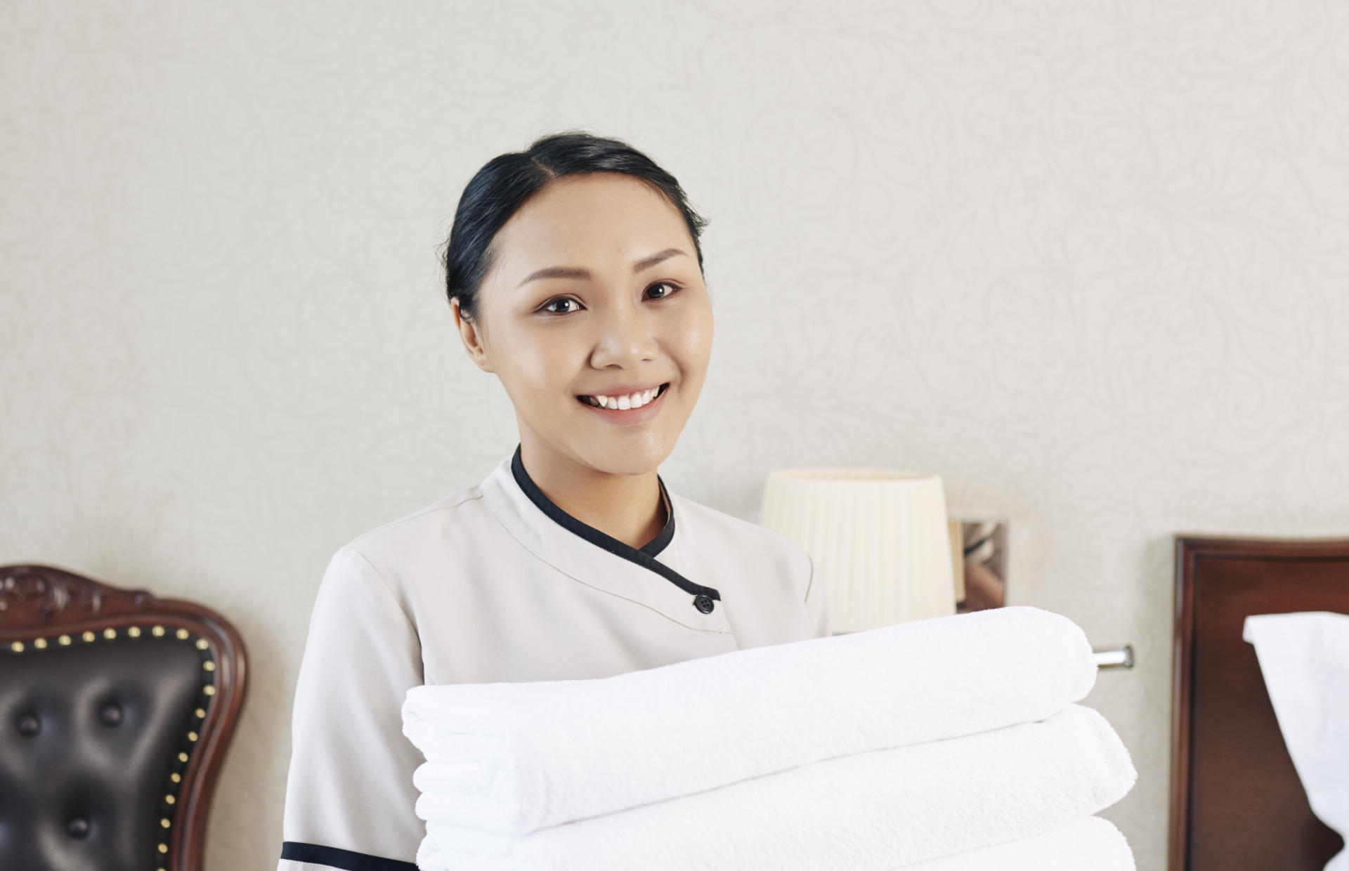 A member of housekeeping holds a stack of folded white towels.