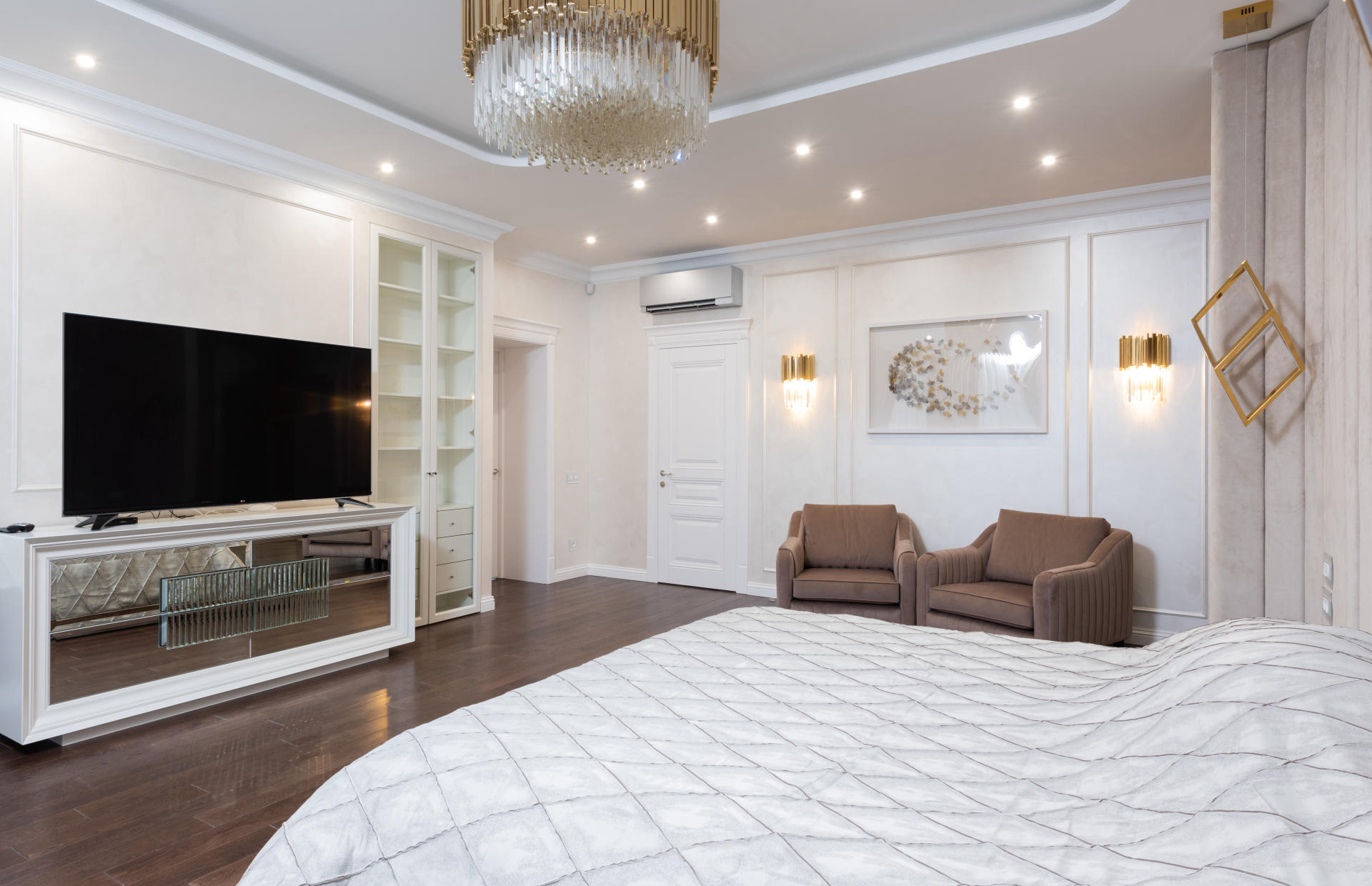 A hotel room is decorated with gold fixtures and white bedding.