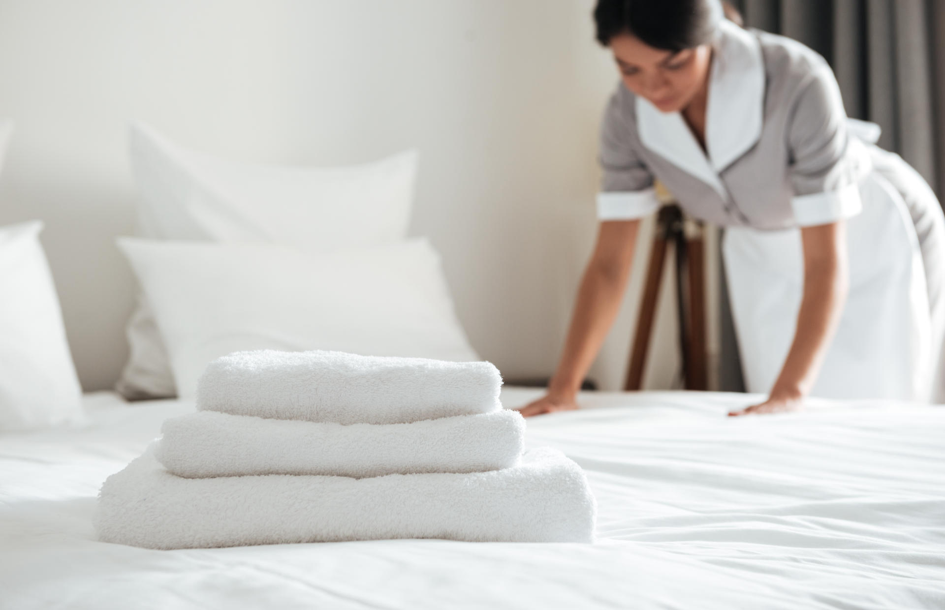 A woman is making up a hotel bed.