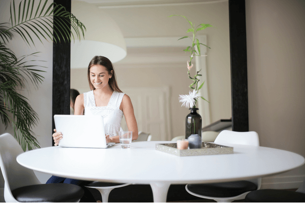 A woman sits a table in front of her computer.