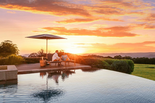 A couple relaxes by the pool at sunset while staying at a Spicers Retreats hotel.